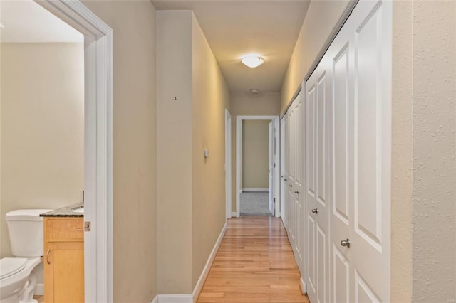 hallway featuring light wood-style floors and baseboards