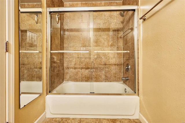 full bath with a textured wall and shower / bath combination with glass door