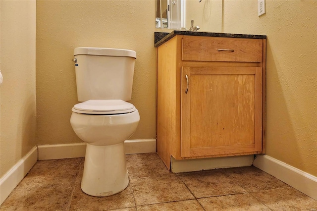 bathroom with toilet, vanity, and baseboards