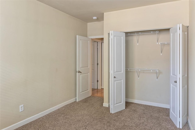 unfurnished bedroom featuring baseboards, carpet floors, and a closet