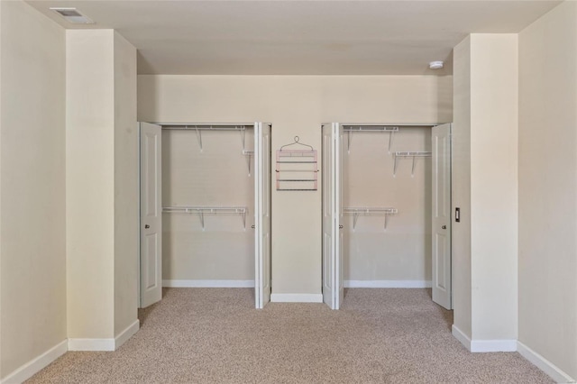 unfurnished bedroom featuring visible vents, two closets, baseboards, and carpet floors