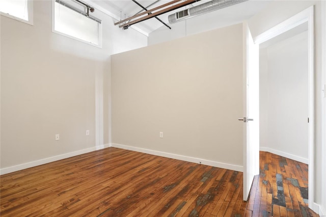 spare room with visible vents, baseboards, and hardwood / wood-style floors