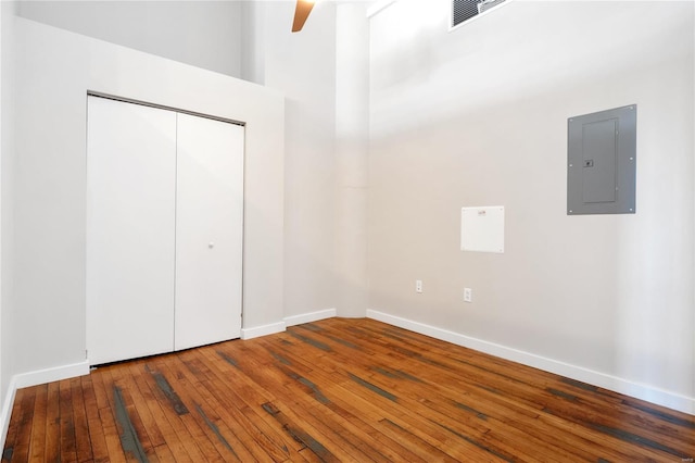 unfurnished bedroom with electric panel, visible vents, baseboards, and hardwood / wood-style flooring