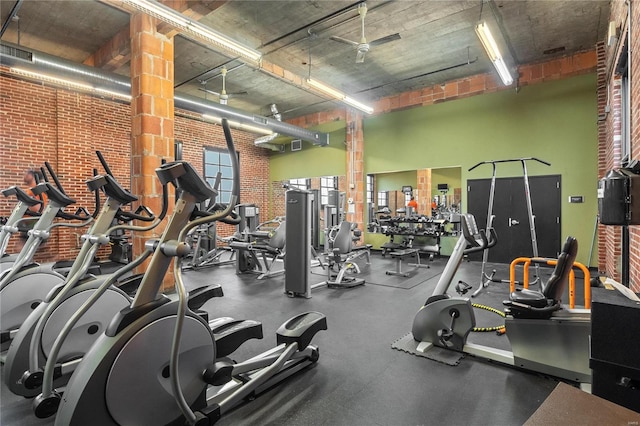 workout area featuring visible vents, brick wall, and a high ceiling