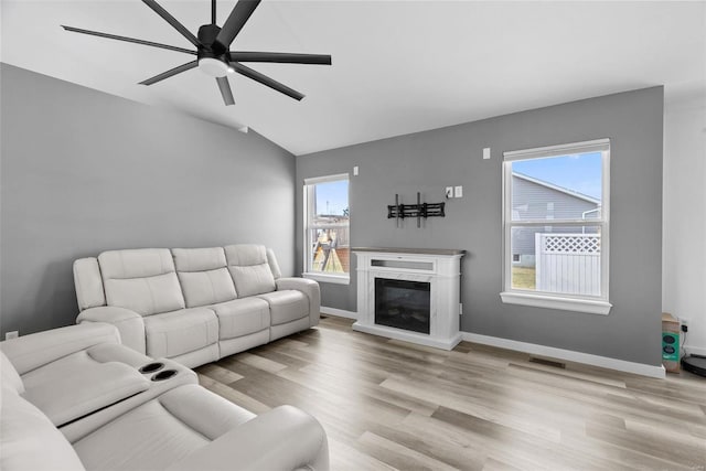 living room with wood finished floors, a ceiling fan, visible vents, baseboards, and lofted ceiling