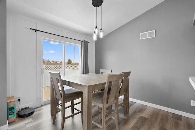 dining area featuring vaulted ceiling, wood finished floors, visible vents, and baseboards