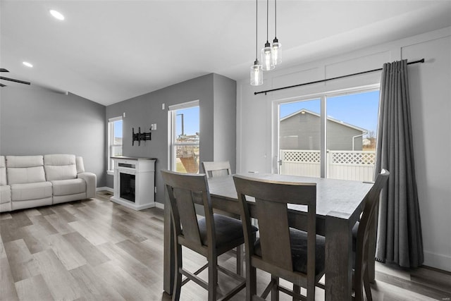 dining area with baseboards, a fireplace, and light wood finished floors