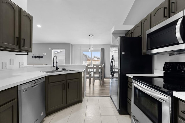 kitchen with light tile patterned floors, a peninsula, a sink, stainless steel appliances, and light countertops