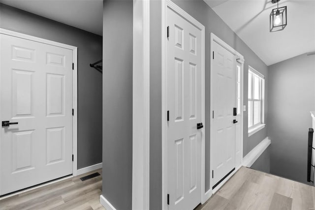 entryway featuring light wood finished floors, visible vents, baseboards, and lofted ceiling