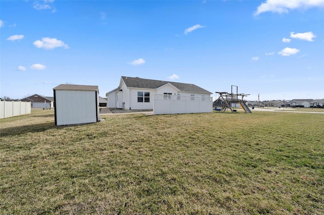 back of property with a playground, fence, a storage shed, a yard, and an outbuilding