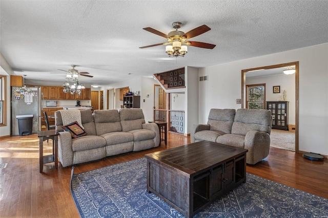 living room featuring hardwood / wood-style floors, stairway, visible vents, ceiling fan, and a textured ceiling