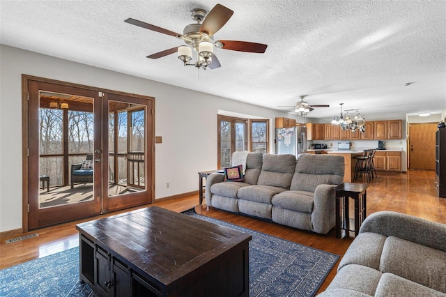 living area with french doors, baseboards, visible vents, and wood finished floors