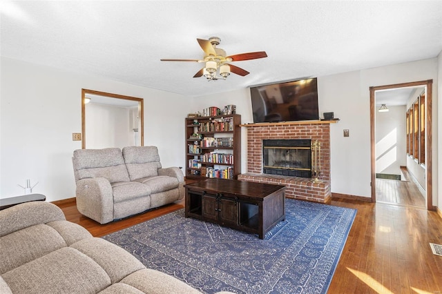 living area featuring visible vents, a fireplace, wood finished floors, a textured ceiling, and a ceiling fan