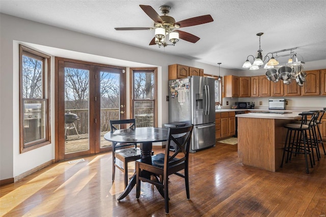 dining area with plenty of natural light, wood finished floors, baseboards, and a textured ceiling