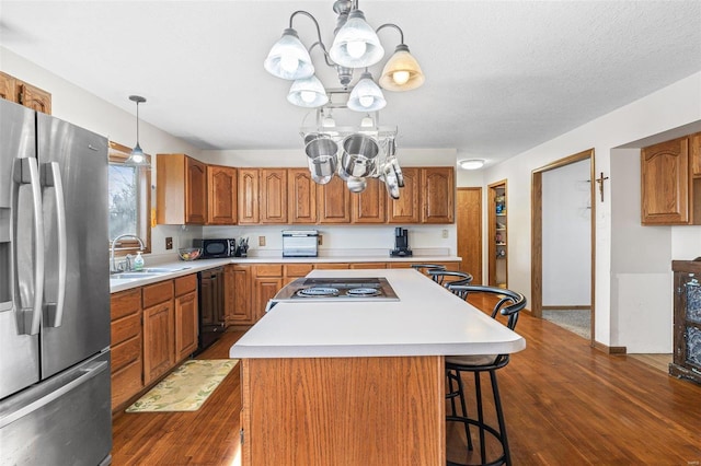 kitchen with a center island, light countertops, brown cabinets, a kitchen breakfast bar, and black appliances