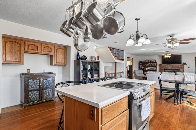 kitchen featuring a kitchen island, a fireplace, dark wood-type flooring, electric stove, and a textured ceiling