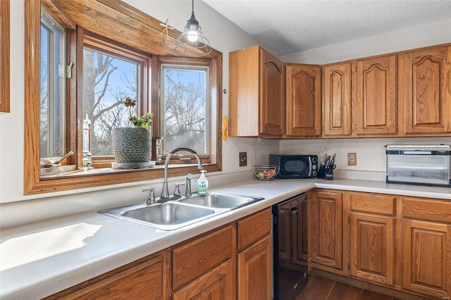 kitchen featuring black appliances, light countertops, brown cabinets, and a sink