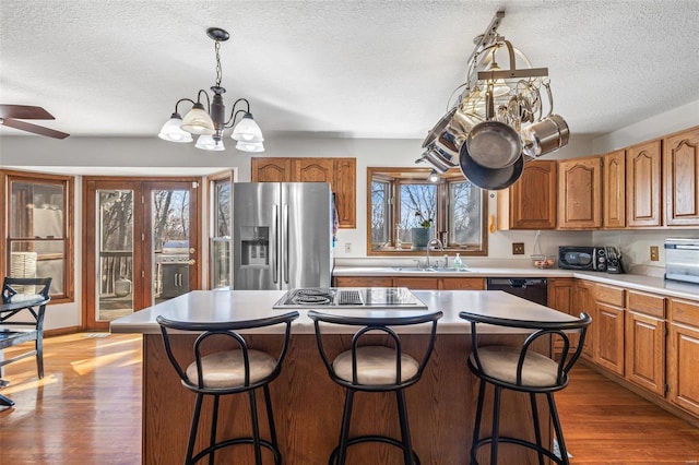 kitchen with brown cabinetry, stainless steel fridge with ice dispenser, and a sink