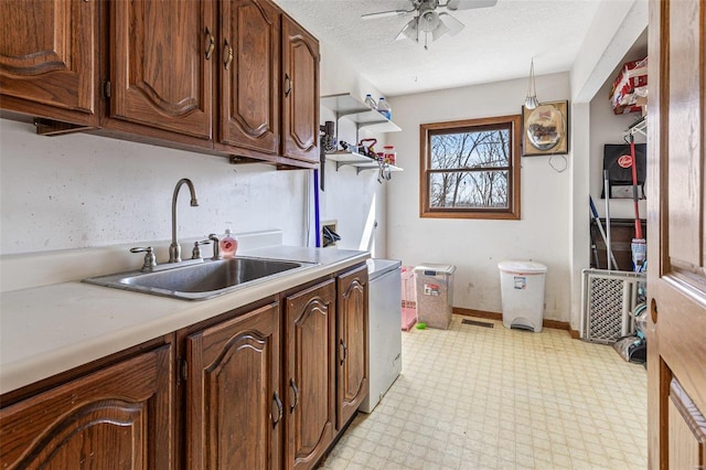 kitchen featuring light floors, ceiling fan, a sink, light countertops, and a textured ceiling