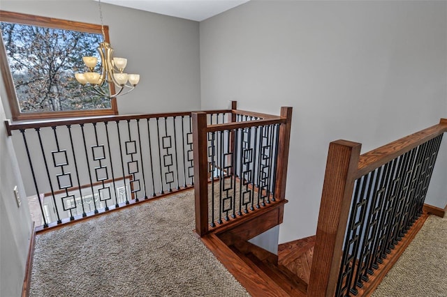 stairs featuring a notable chandelier and carpet