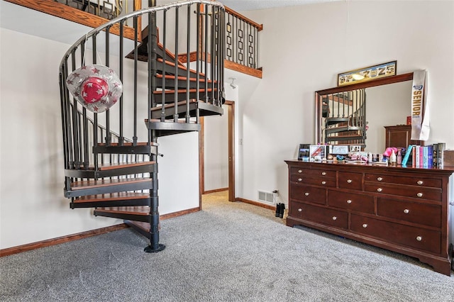 staircase featuring a high ceiling, carpet flooring, baseboards, and visible vents