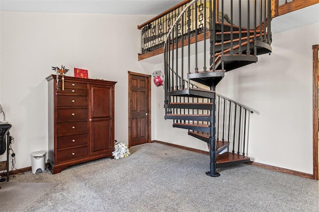 staircase featuring a towering ceiling, baseboards, and carpet floors