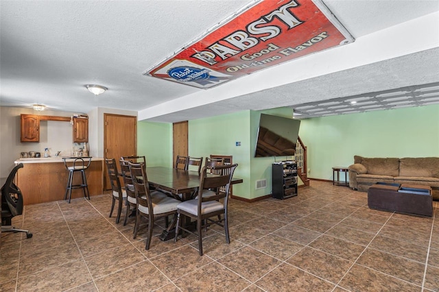 dining area with visible vents, baseboards, stairs, a textured ceiling, and dark tile patterned floors