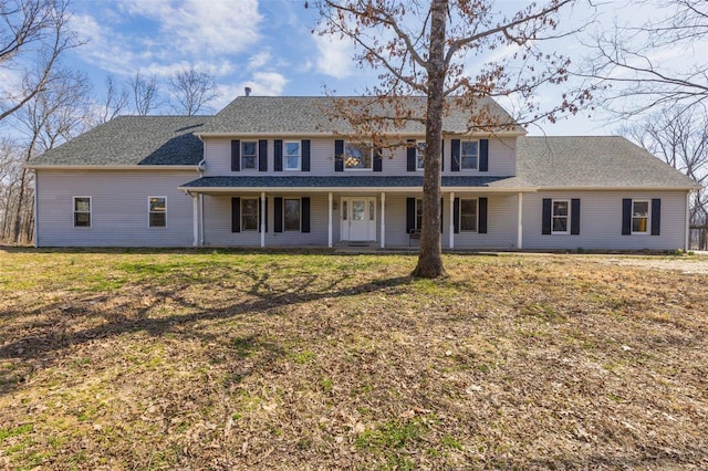 colonial-style house with a front lawn, covered porch, and a shingled roof