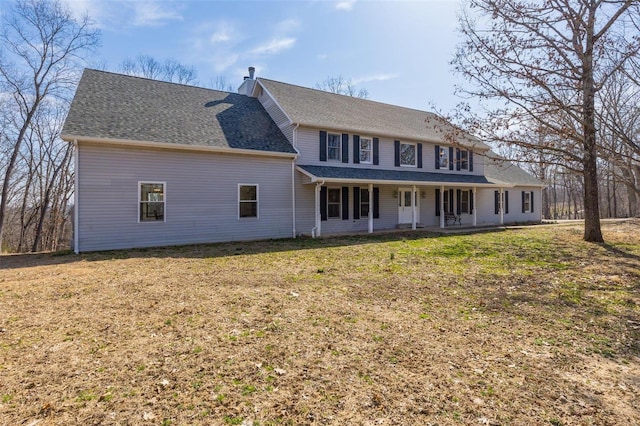 rear view of property with a yard and roof with shingles