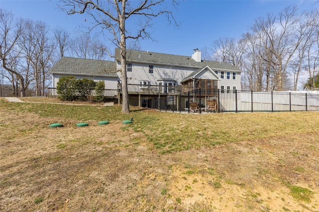 rear view of property with fence, a lawn, a chimney, a deck, and a patio