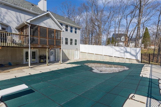 view of pool featuring fence, a patio, and a sunroom