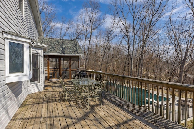 wooden deck featuring outdoor dining area, a fenced in pool, and a sunroom