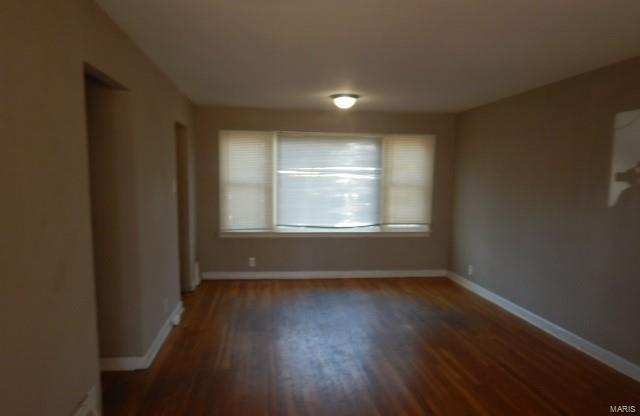 spare room with baseboards and wood finished floors