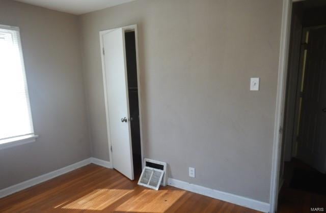 spare room with wood finished floors, visible vents, and baseboards