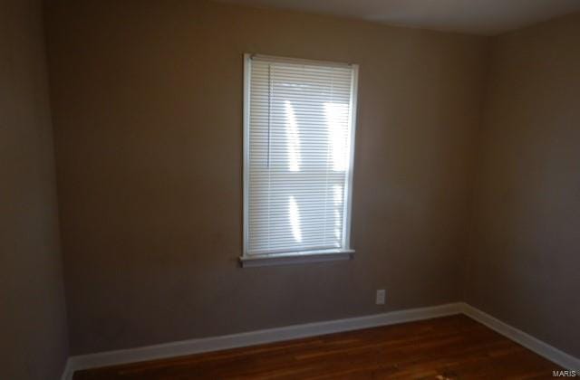 unfurnished room featuring baseboards and dark wood-type flooring