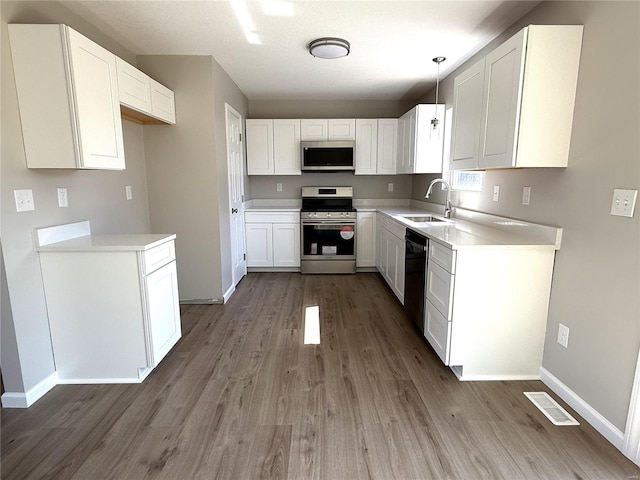 kitchen with visible vents, a sink, wood finished floors, white cabinetry, and stainless steel appliances