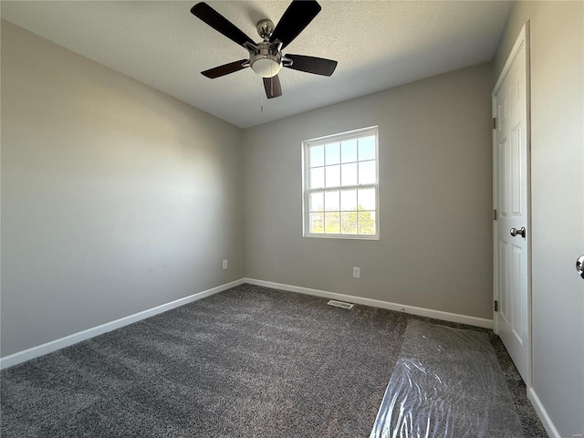 unfurnished bedroom with dark colored carpet, visible vents, baseboards, and a textured ceiling