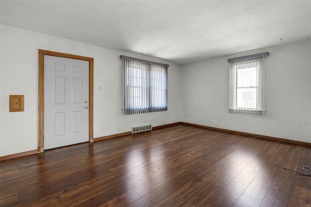 empty room featuring visible vents, wood-type flooring, and baseboards