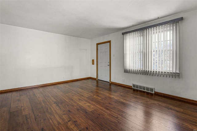 spare room featuring visible vents, baseboards, and dark wood-type flooring