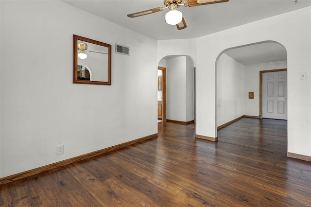 unfurnished room with visible vents, ceiling fan, baseboards, wood finished floors, and arched walkways