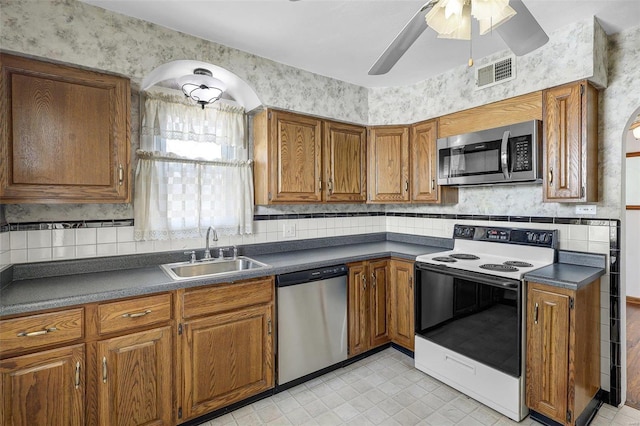 kitchen with dark countertops, visible vents, brown cabinetry, stainless steel appliances, and a sink