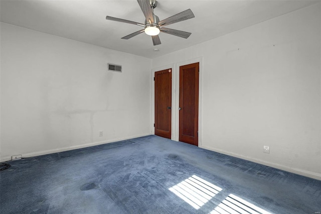 carpeted empty room with visible vents, baseboards, and a ceiling fan