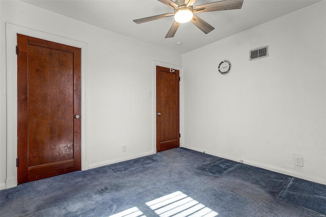 spare room featuring visible vents, a ceiling fan, and dark carpet