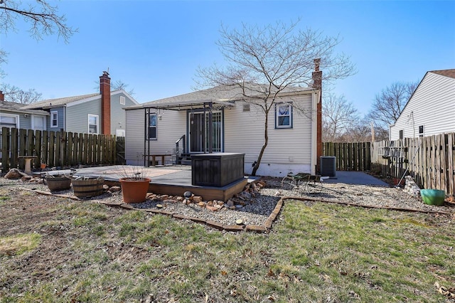 back of house featuring a fenced backyard, central AC, a chimney, a deck, and a lawn