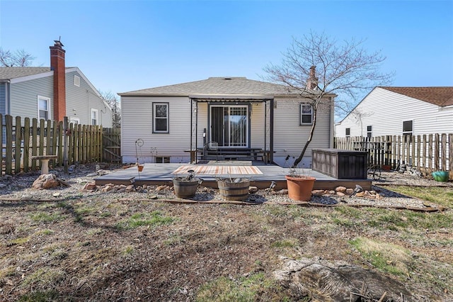 rear view of property featuring a wooden deck, roof with shingles, and a fenced backyard