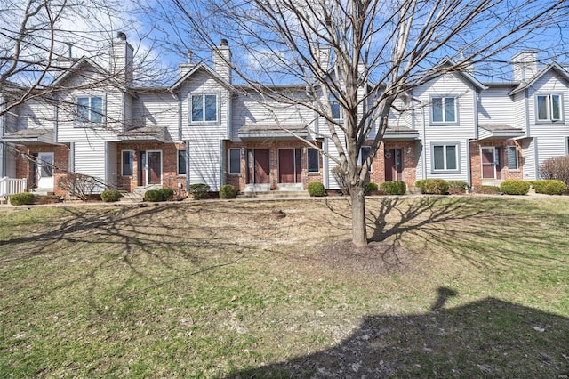 view of front of home with a front lawn, brick siding, and a chimney