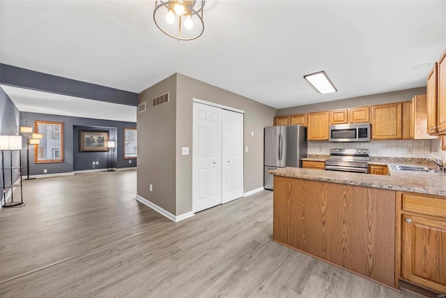 kitchen featuring visible vents, backsplash, open floor plan, stainless steel appliances, and a sink