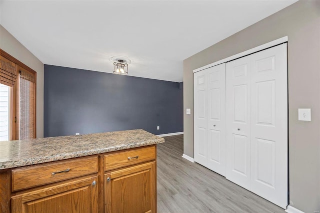 kitchen featuring light wood-style flooring, baseboards, and brown cabinets