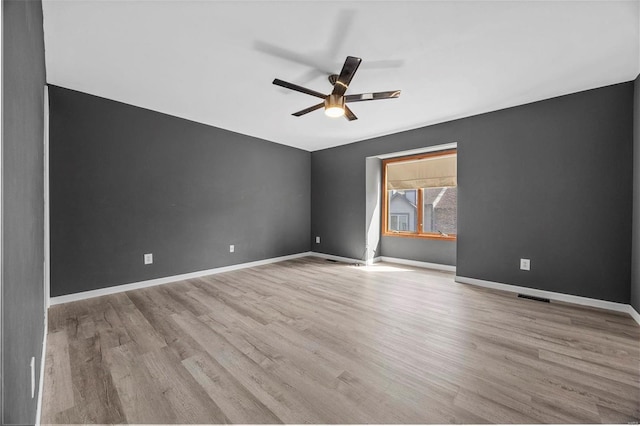 spare room featuring visible vents, baseboards, a ceiling fan, and wood finished floors