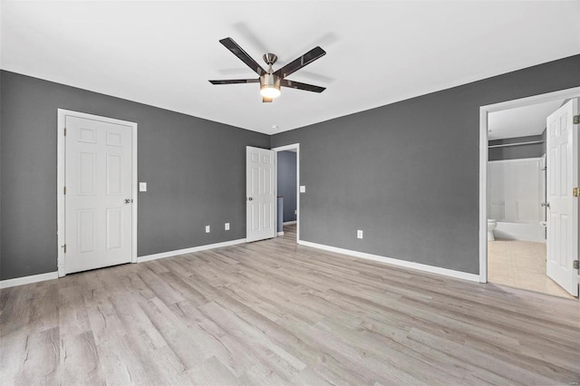 unfurnished bedroom featuring a ceiling fan, wood finished floors, baseboards, and ensuite bathroom